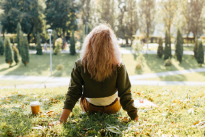 Photo of a woman sitting on the grass on a sunny day. This photo represents how meditation tips in Atlanta, GA can help you manage and reduce your anxiety symptoms.
