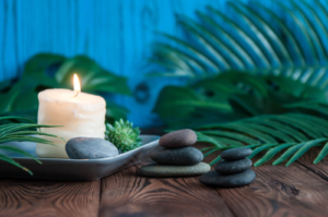 Photo of a lit candle with rocks and a plant on a table. Anxiety can feel overwhelming at times. Learn meditaition tips in Atlanta, GA from an anxiety therapist.