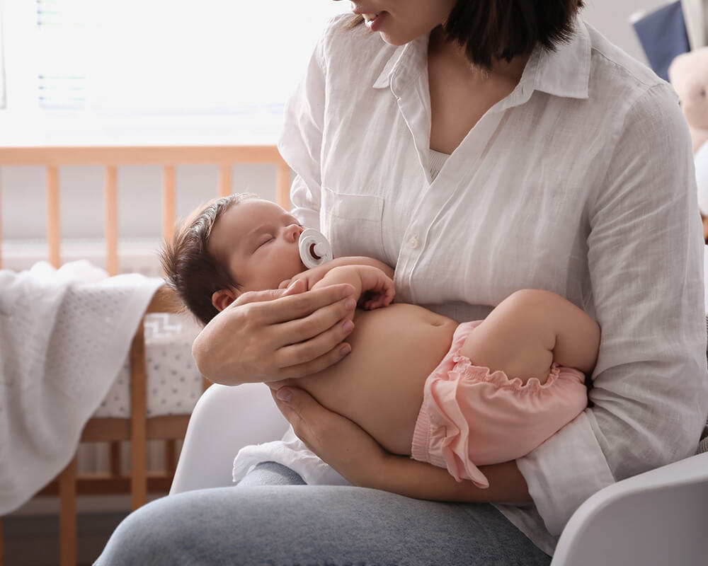 Image of a mother holding a sleeping baby. If you are struggling after birth, learn how postpartum therapy in Atlanta, GA can help you explore and manage your emotions.