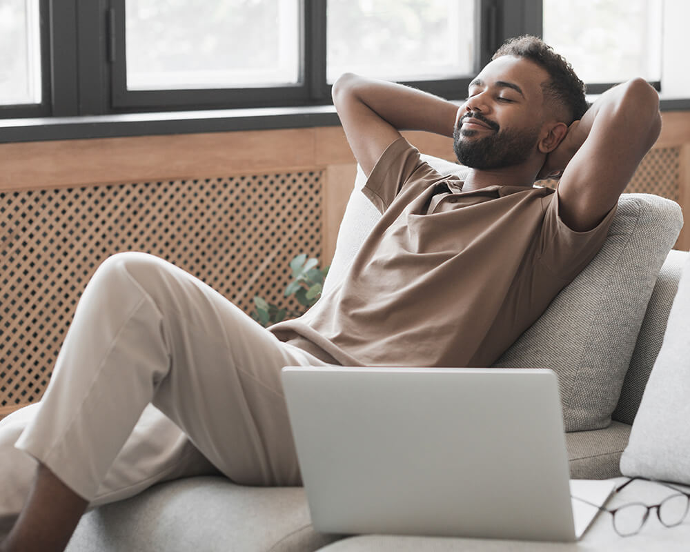 Photo of a man sitting on a couch with his hands behind his back looking relaxed. This photo represents how therapy for stress management in Atlanta, GA can help you overcome your stress symptoms and live a stress free life.