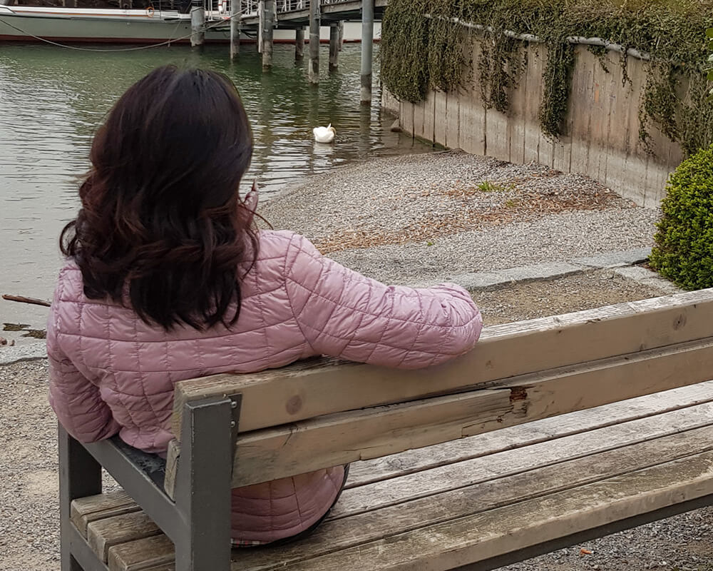 Photo of a woman sitting outside on a bench facing water. Are you struggling with facing the loss of someone? With grief counseling in Atlanta, GA you can begin to cope with your loss and manage your symtpoms.