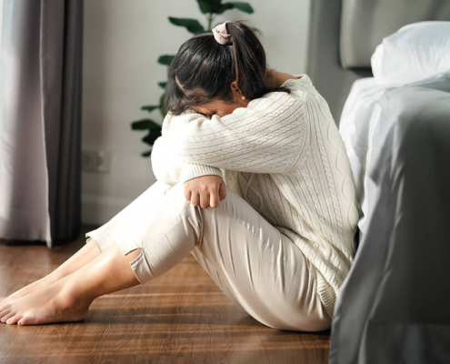 Photo of a woman sitting on the floor with her head on her knees. This photo represents how without stress and anxiety counseling in Atlanta, GA you may be unable to relieve your stress and anxiety symptoms without support.
