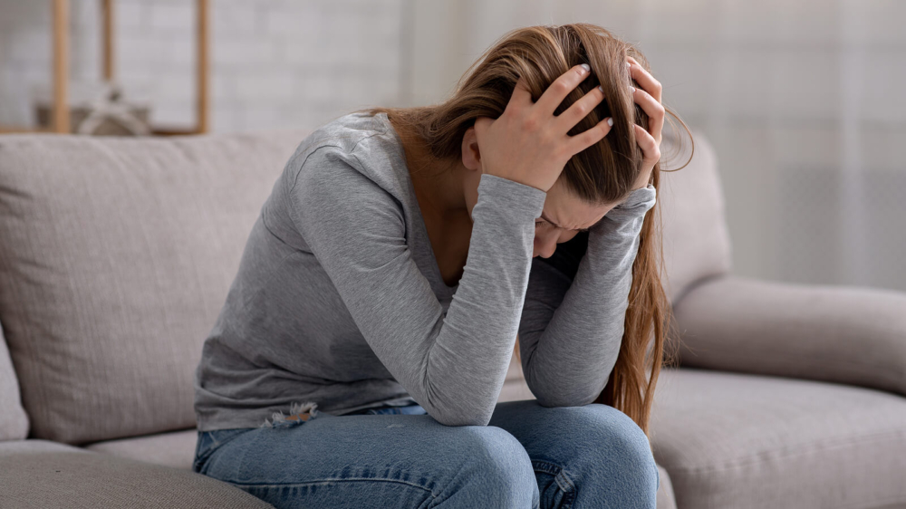 Photo of a woman holding her head in her hands crying. This photo represents how overwhelming grief can be for someone. Discover how grief counseling in Atlanta, GA can help you begin to cope with your grief symptoms.