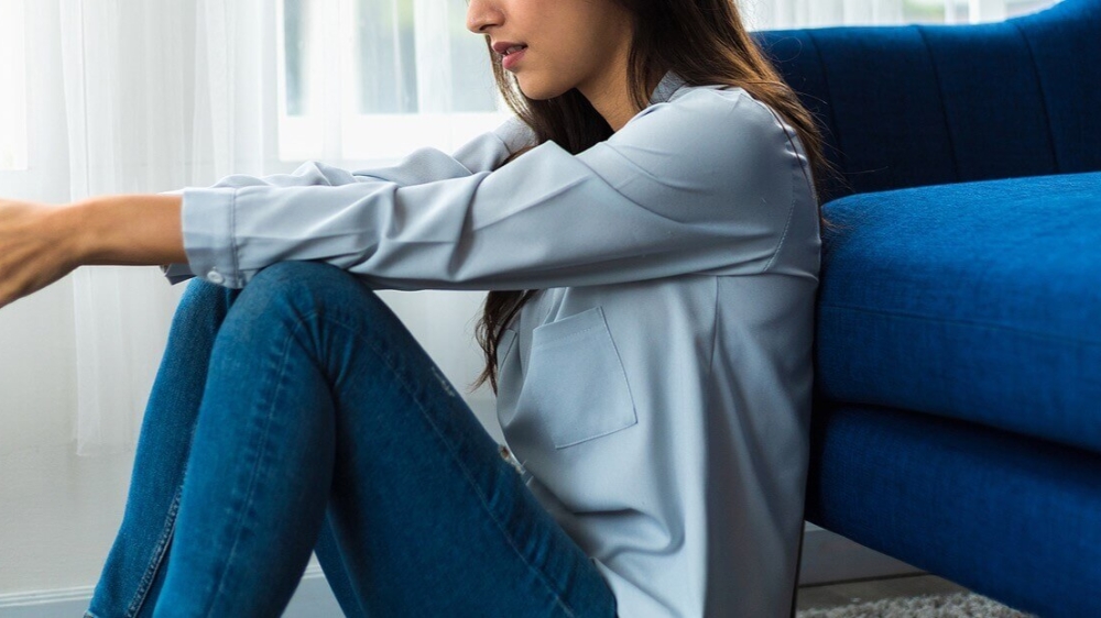 Photo of a woman sitting on the floor with her arms on her knees representing how depression symptoms can become too much. With depression therapy in Atlanta, GA you can find the support you need to begin managing your symptoms.