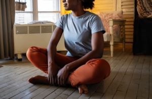 Photo of an African American woman sitting on the floor cross legged and smiling. This photo represents the ways you can begin to manage your intrusive thoughts. Learn how anxiety therapy in Atlanta, GA can provide support in overcoming your symptoms.