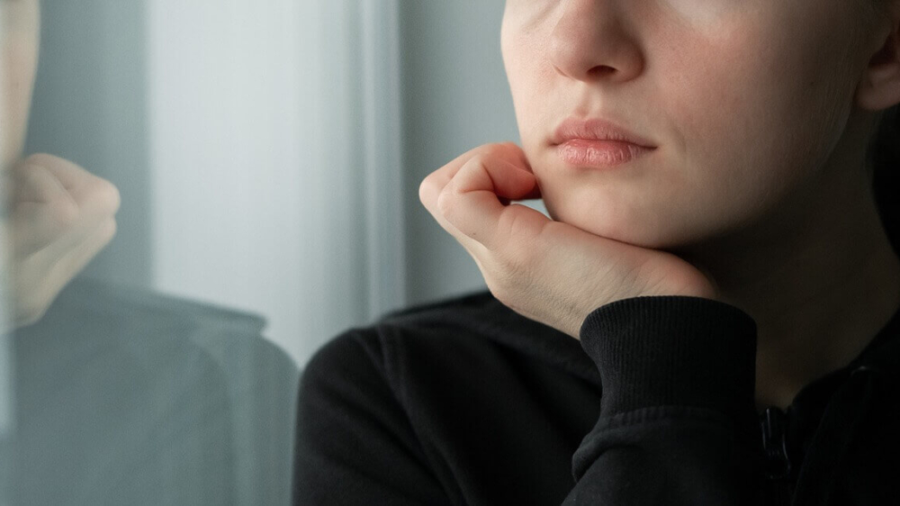 Photo of a woman holding her head on her hand and looking through a window. Are you struggling with intrusive thoughts? With anxiety therapy in Atlanta, GA you can gain support and begin managing your anxiety symptoms.