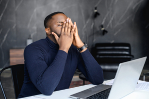 Photo of a man sitting at his desk with his hands on his face and his eyes closed. Depression can be overwhelming and keep you from living your life. If you're not sure if depression therapy in Atlanta, GA is right for you, read tips from a depression therapist on why you should seek help.