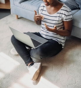 Photo of a woman sitting on the floor using her laptop for work. Discover how you can stay motivated and stress-free when working from home. Receive more support with stress therapy in Atlanta, GA.