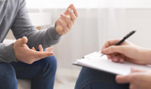Photo of a man speaking with a therapist who's taking notes. Interested in grief counseling in Atlanta, GA but not sure what to expect? With a skilled grief therapist you can begin to manage your symptoms in a healthy way.