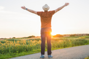 Photo of a man standing outside during sunset with his arms outstretched in a positive way. Struggling with your stress symptoms? With therapy for stress in Atlanta, GA you can begin learning the techniques to manage your stress in a healthy way.