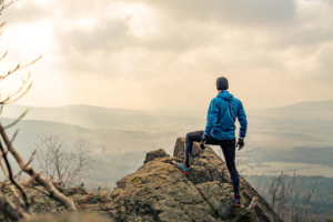 Photo of a man standing on top of a cliff looking out over a valley. Discover how anxiety therapy in Atlanta, GA can help you face your health anxiety symptoms and begin working to manage them in a positive way.