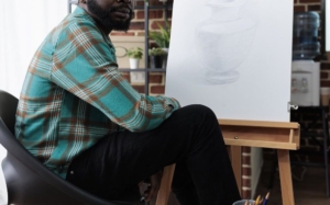 Photo of an African American man sitting in front of an easel. Health anxiety can be overwhelming when not managed. Find support with an anxiety therapist on controlling your symptoms effectively with anxiety therapy in Atlanta, GA.