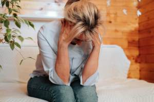 Photo of an upset woman holding her head in her hands looking down. Discover how grief counseling in Atlanta, GA can help you support you after the death of a loved one so you can begin healing.