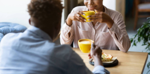 Photo of a woman and man sitting at a table drinking coffee and smiling. Learn to improve your mood with the help of depression therapy in Atlanta, GA.