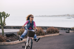 Photo of a woman smiling and riding a bike happily near the beach. Social media can make it difficult to control our moods. Learn how depression therapy in Atlanta, GA can support you.