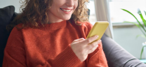 Photo of a smiling woman using her cell phone accessing social media. Struggling to balance your mood when using social media? Learn how to effectively back away from social media and how depression therapy in Atlanta, GA can help you.