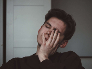 Photo of a stressed man touching his face with his eyes closed. Learn what your anxiety triggers are and how to prevent them from happening with the help of anxiety therapy in Atlanta, GA.