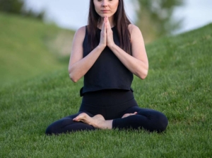 Photo of a woman sitting in the grass practicing meditation. Learn practical ways to manage your perfectionism with the help of a skilled anxiety therapist in anxiety therapy in Atlanta, GA.