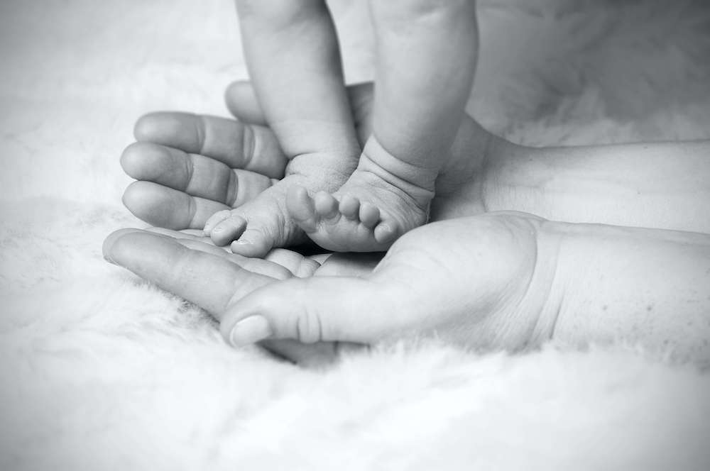 Image of someone holding baby's feet in their hands. If your struggling with birth trauma, learn how postpartum therapy in Atlanta, GA can help you.