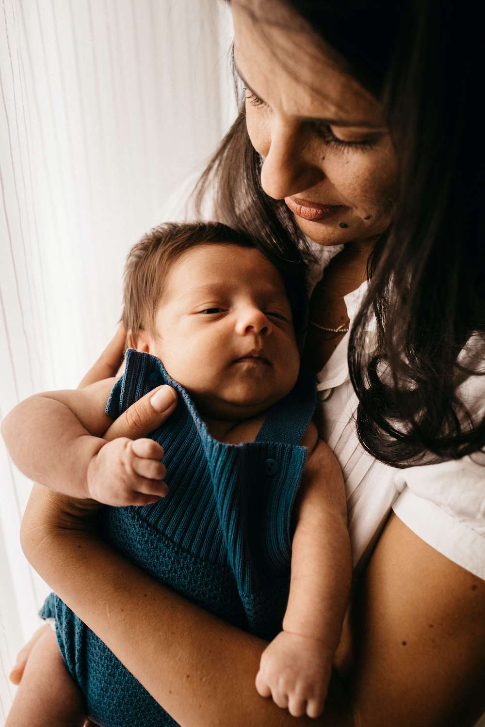 Image of a happy mother holding her sleeping baby in her arms. Discover how postpartum therapy in Atlanta, GA can help you cope with your birth trauma symptoms.