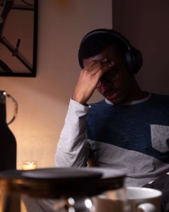 Photo of an anxious young man with headphones on putting his hand on his forehead. Do you struggle managing your anxious thoughts? Learn how anxiety therapy in Atlanta, GA can help you begin challenging your thoughts.