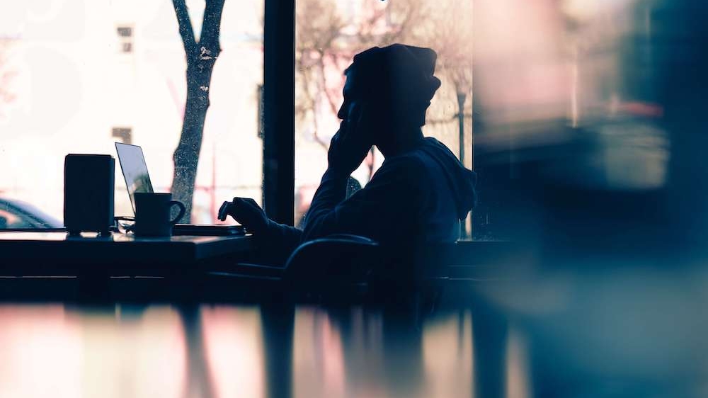 Photo of a young man sitting at a cafe using his laptop. Do you struggle to control your anxious thoughts? Learn how anxiety therapy in Atlanta, GA can help you manage them.