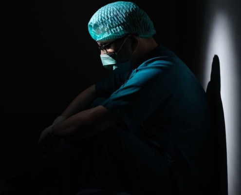 Image of a medical professional sitting on the floor in the dark. Overcome your depression so you can refocus on your work with the help of depression therapy in Atlanta, GA.
