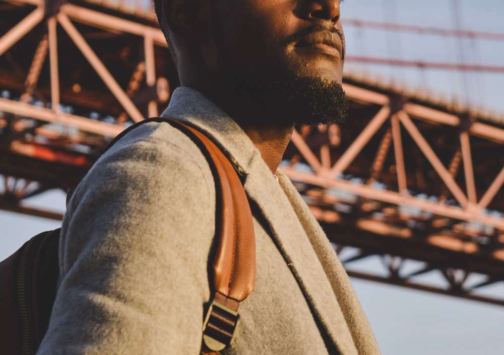 Photo of an African American man standing outside under a bridge wearing a backpack and looking out into the distance. Learn how managing your anxious thoughts can help you overcome your anxiety with the help of anxiety therapy in Atlanta, GA.