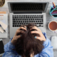 Image of a stressed woman with her hands in her hair sitting over her laptop. Do you struggle with workplace anxiety? Learn how anxiety therapy in Atlanta, GA and anxiety therapist can help you cope with the anxiety symptoms.