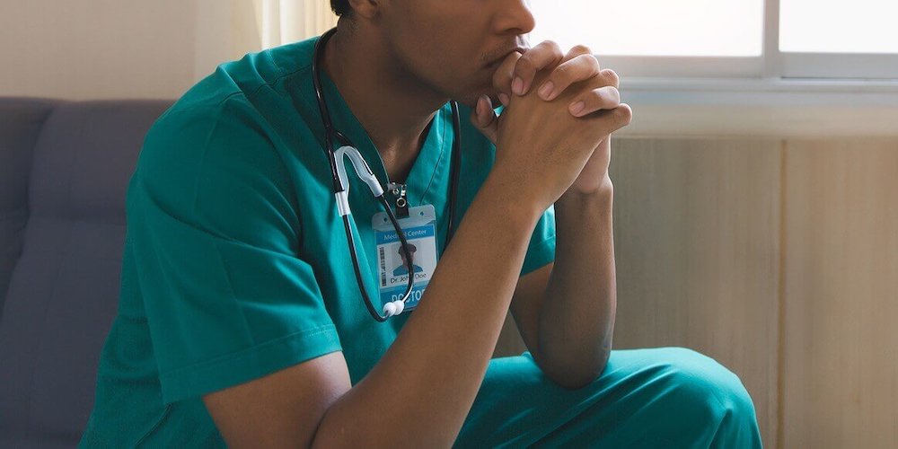 Image of a stressed man wearing scrubs resting his hand against his mouth. Begin managing your depression symptoms with the help of a skilled depression therapist. Work through your challenges with the help of depression therapy in Atlanta, GA.