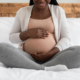 A smiling woman rubs her pregnant stomach. Learn how a postpartum therapist in Atlanta, GA can offer support in addressing depression. Search for "postpartum therapist atlanta" for online depression therapy in Atlanta, GA today.