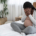 A pregnant woman covers her face while sitting on a bed. This could represent the postpartum pain that a postpartum therapist in Atlanta, GA can address. Learn more about therapy for birth trauma in Atlanta, GA by searching for "postpartum therapist atlanta" today.