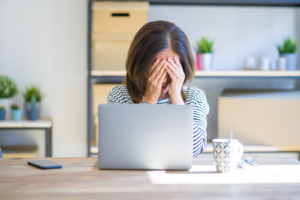 A woman covers her face while sitting in front of a laptop. This could represent the stress of finding the right therapist. Learn how a Psypact therapist in Atlanta, GA can help you from the comfort of home. Search for stress therapy in Atlanta, GA or an online anxiety therapist in Atlanta, GA today. 