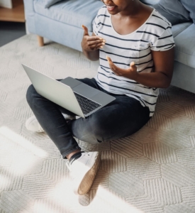 A close up of a woman sitting on the floor with a laptop while talking over a video call. This could represent the ease of meeting with a Psypact therapist in Atlanta, GA. Learn how they can offer stress therapy in Atlanta, GA and other services by searching for "anxiety therapist atlanta, ga" today. 