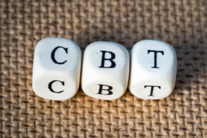 A close up of dice with the letters CBT for Cognitive Behavioral Therapy. Learn how this can help you address health anxiety in Atlanta, GA and the support that online anxiety therapy in Atlanta, GA can offer. Learn more about the help an online anxiety therapist in Atlanta, GA can offer today. 
