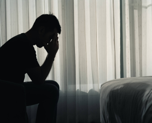 A silhouette of a man holding their head while in a dark room. This could represent the pain of depression that a depression therapist in Atlanta, GA can address. Learn more about depression therapy in Atlanta, GA and how online depression therapy in Atlanta, GA can offer remote support.