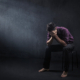 A man sits with his hands over his face in a room with a single ray of light shining down. This could represent the stress of existential anxiety that online anxiety therapy in Atlanta, GA can offer help in overcoming. Learn more about stress and anxiety counseling in Atlanta, GA or other services like anxiety therapy in Atlanta, GA.