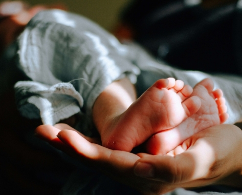 Image of a mom holding her newborn baby's feet. Overcome the stress of postpartum with the help of a skilled postpartum therapy in Atlanta, GA.