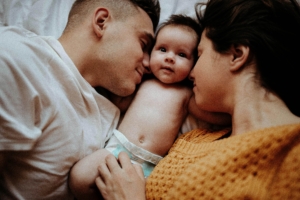 Photo of parents cuddling with their baby. Strengthen your bond with your baby and partner through postpartum counseling in Atlanta, GA. A postpartum therapist in Georgia can help you deal with depression and anxiety.