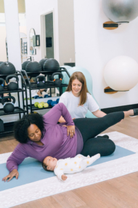 A mother performs a side-lying exercise while her baby rests nearby, guided by a postpartum therapist in Atlanta, GA who specializes in postpartum therapy in Atlanta, GA and Alpharetta postpartum anxiety treatment to improve strength and mental health.
