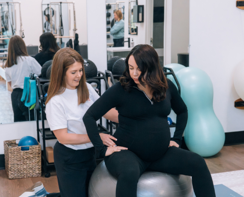 A postpartum therapist in Atlanta, GA helps a pregnant woman with gentle core exercises on a stability ball, supporting her through postpartum therapy in Atlanta, GA and offering care that complements postpartum anxiety treatment in Atlanta.