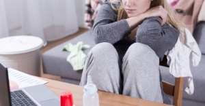 An exhausted mother sits in loungewear, overwhelmed by baby bottles and charts, representing the need for postpartum counseling in Atlanta and support from a postpartum therapist in Atlanta, GA. 