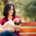 A new mother sits on a park bench holding her baby, appearing overwhelmed—symbolizing the emotional weight that postpartum therapy in Atlanta, GA or postpartum anxiety treatment in Atlanta can help address.