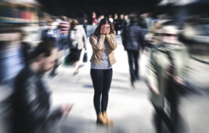 A woman covers her face in a blurred, crowded street—illustrating the panic and overwhelm that may benefit from Alpharetta postpartum anxiety treatment or anxiety therapy in Atlanta, GA. 