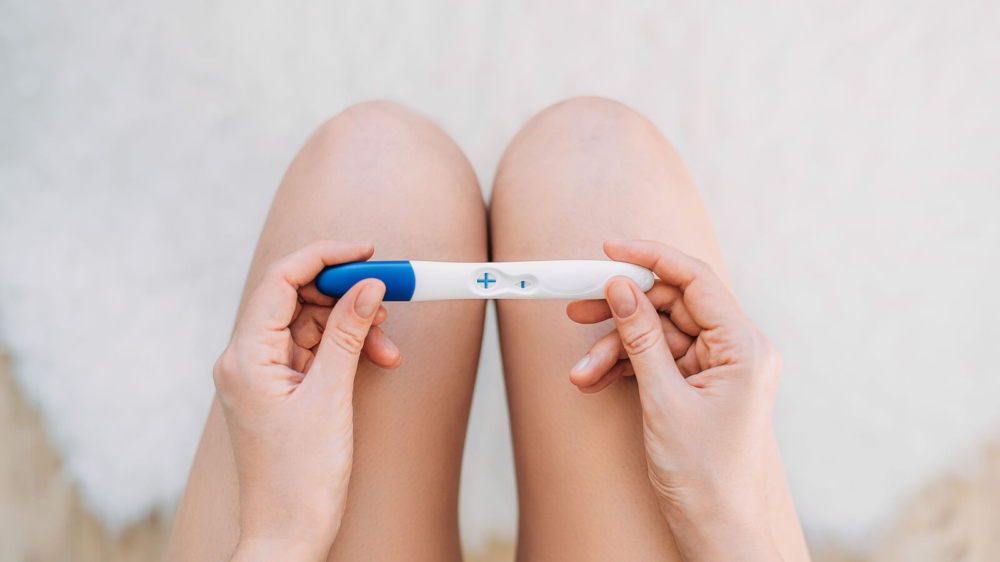 A woman holds a positive pregnancy test, reflecting mixed emotions of hope and fear while seeking postpartum therapy in Atlanta, GA, postpartum counseling Atlanta, postpartum anxiety treatment Atlanta, and Alpharetta postpartum anxiety treatment.