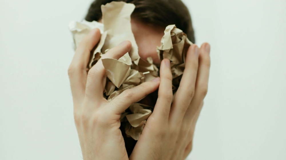 Stressed man covering his face with crumpled paper, capturing overwhelm and racing thoughts. Support is available through anxiety therapy in Atlanta, GA, meeting with an anxiety therapist in Atlanta, GA, or starting therapy for anxiety in Atlanta, GA.