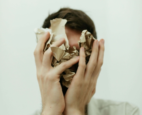Stressed man covering his face with crumpled paper, capturing overwhelm and racing thoughts. Support is available through anxiety therapy in Atlanta, GA, meeting with an anxiety therapist in Atlanta, GA, or starting therapy for anxiety in Atlanta, GA.