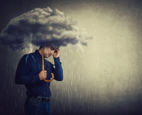 A man stands under a storm cloud, holding an umbrella as rain pours—capturing the heaviness of loss and worry. Support like grief counseling in atlanta, ga with a compassionate grief therapist in atlanta, ga can also include therapy for anxiety in atlanta, ga to ease the pressure.
